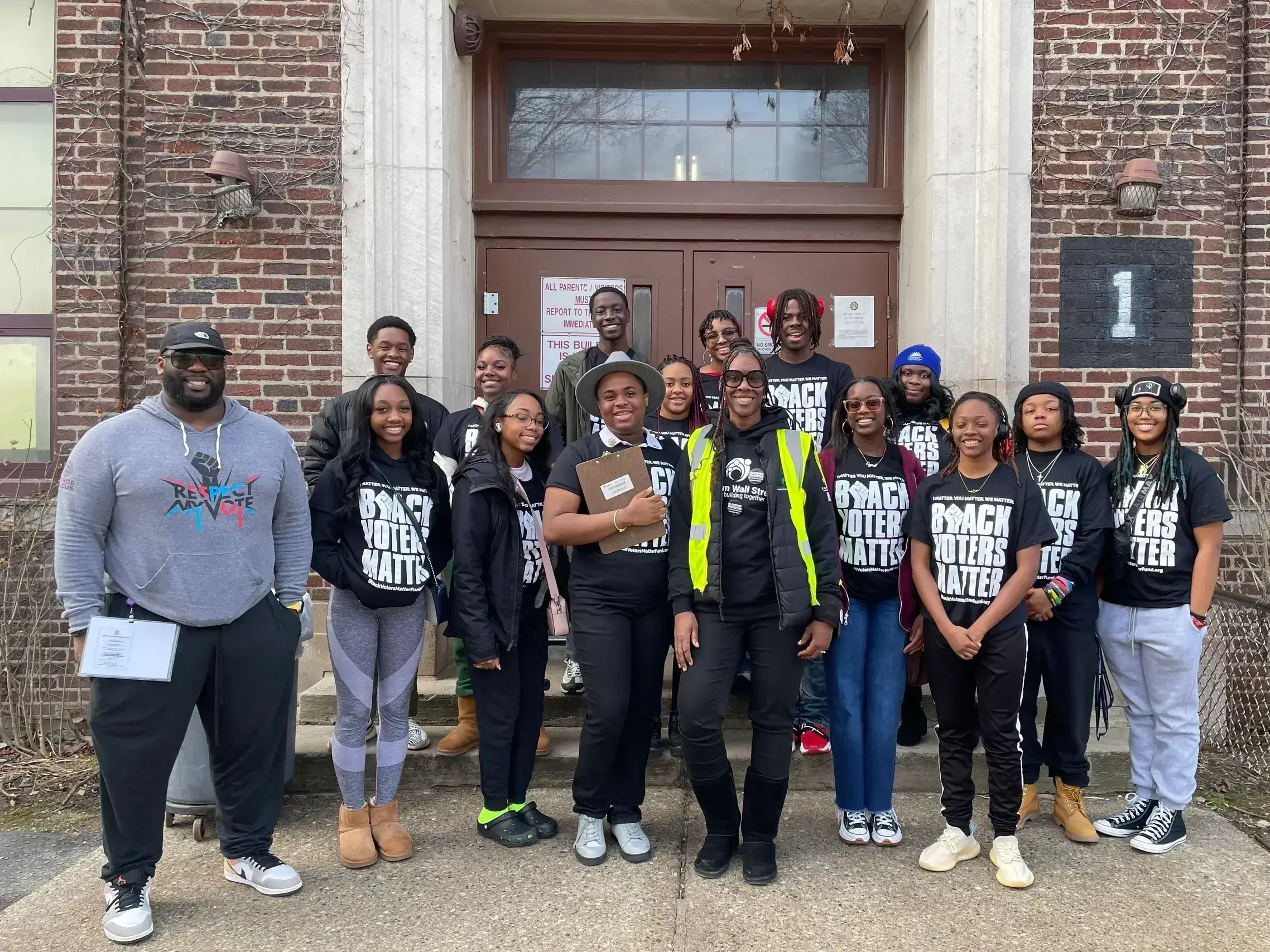 Diverse youth group posing outside brick school