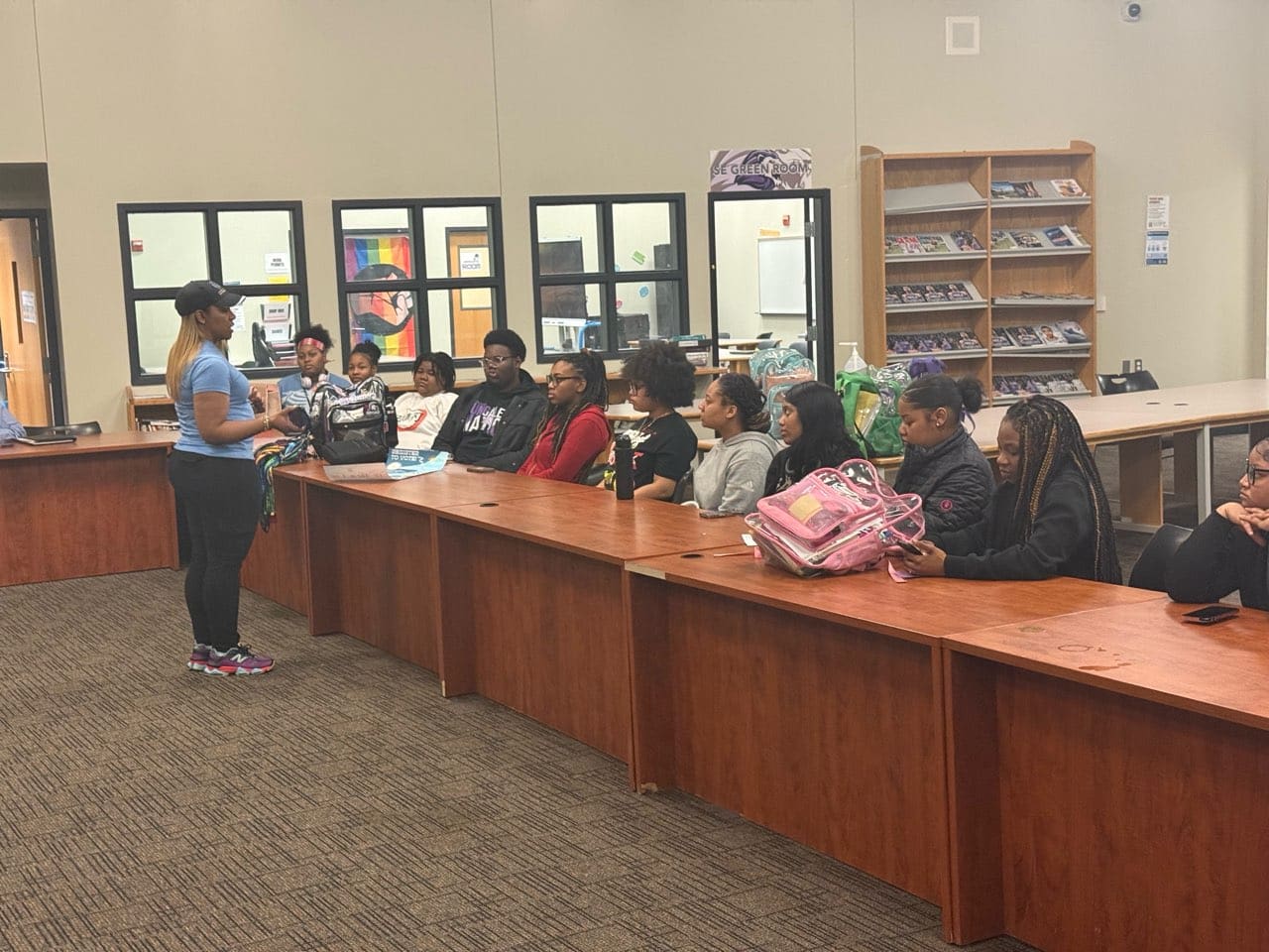Instructor addressing students at long library table